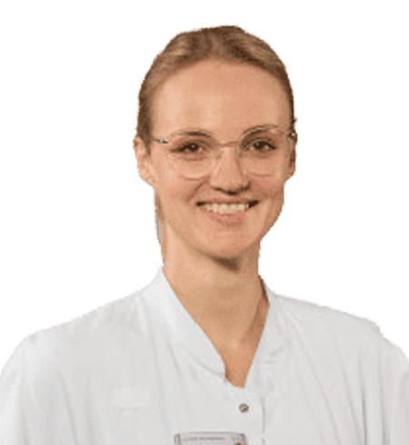 Eine Frau mit Brille und blondem Haar lächelt und trägt einen weißen Arztkittel. Der Hintergrund ist schlicht.