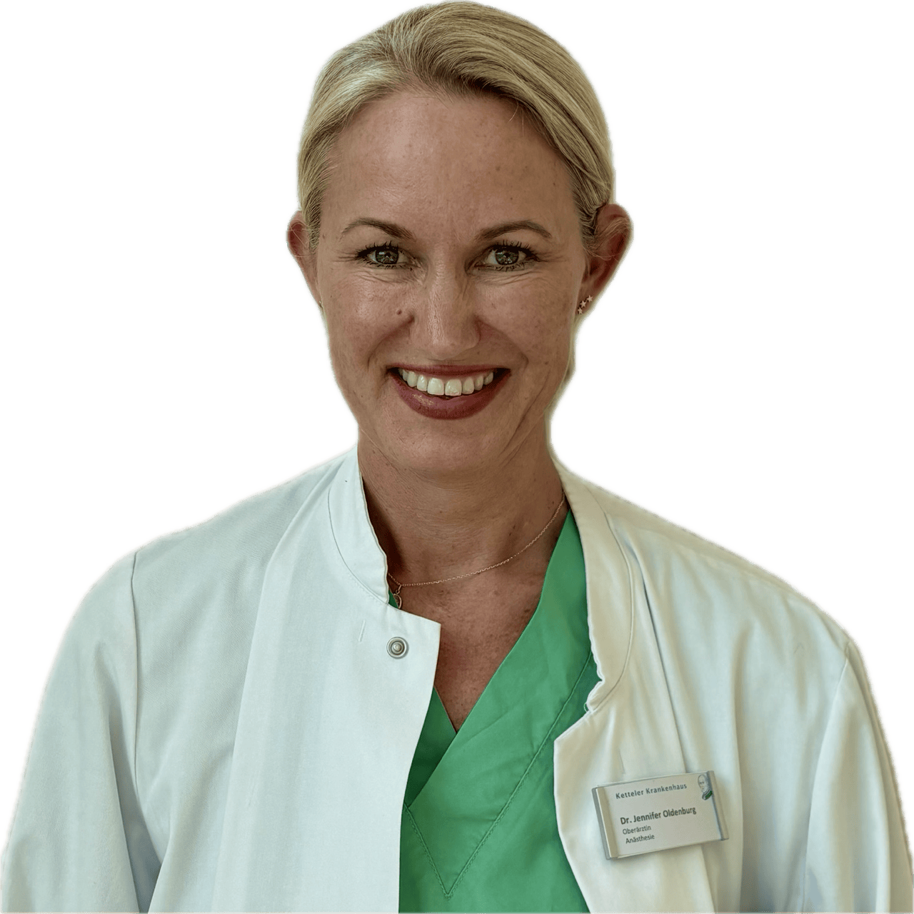Dr. Jennifer Oldenburg, eine Anästhesistin, trägt einen weißen Kittel und grüne OP-Kleidung mit einem Namensschild.